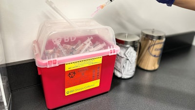 A BD Sharps Collector full of used syringes.