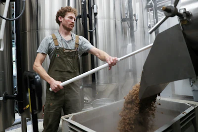 Brewer Scott Peterson retrieves spent grain from a lauterton while brewing a German-style Pilsner at Von Ebert Brewing in Portland, Ore., Sunday, Oct. 22, 2023.
