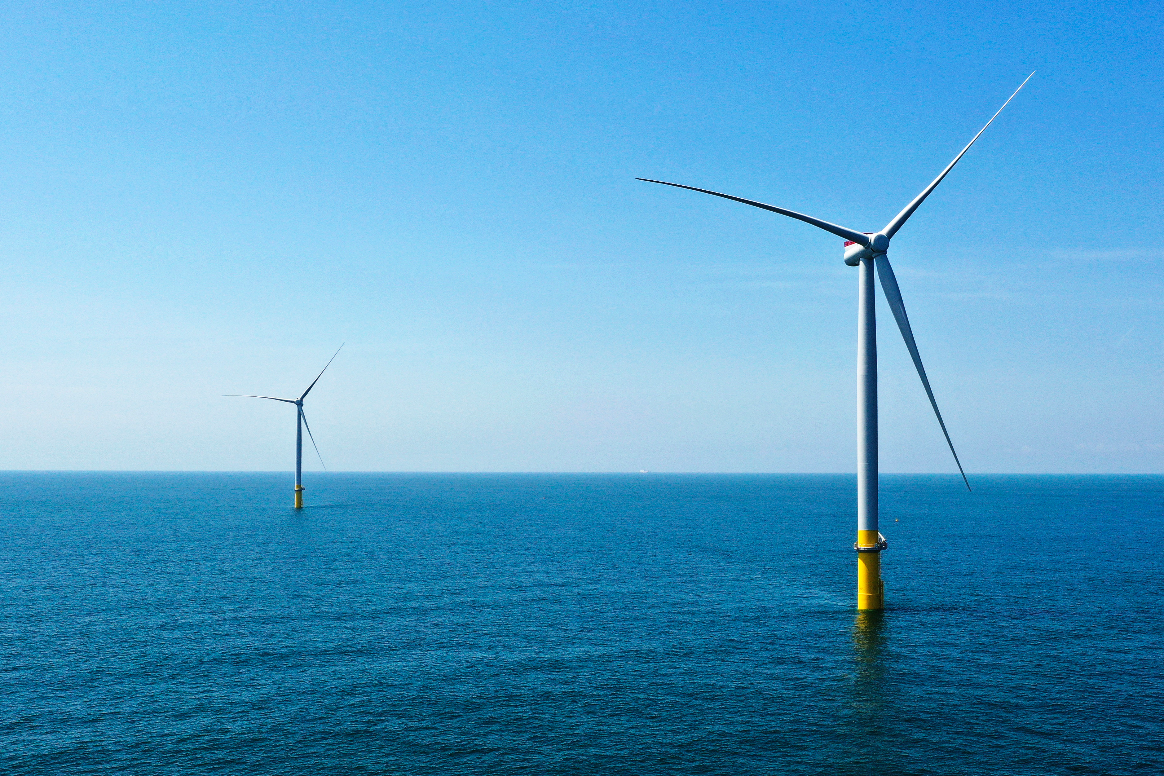 Two of the offshore wind turbines stand off the coast of Virginia Beach, Va., Monday, June 29, 2020.