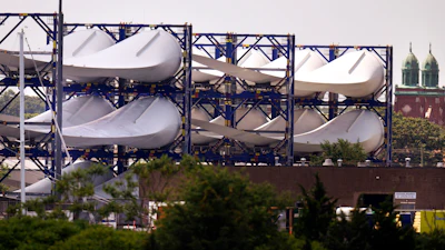 Giant wind turbine blades for the Vineyard Winds project are stacked on racks in the harbor, July 11, 2023, in New Bedford, Mass.