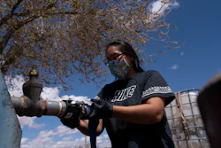 Raynelle Hoskie attaches a hose to a water pump outside a tribal office on the Navajo reservation, Tuba City, Ariz., April 20, 2020.