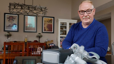 Jeffrey Reed, who experienced persistent sinus infections and two bouts of pneumonia while using a Philips CPAP machine, poses with the device at his home, Oct. 20, 2022, in Marysville, Ohio.