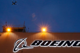 An airplane flies over a sign on Boeing's 737 delivery center, Oct. 19, 2015, at Boeing Field in Seattle.