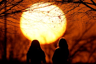 People watch the sunset at a park on an unseasonably warm day, Feb. 25, 2024, in Kansas City, Mo.