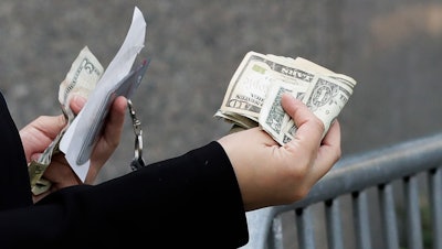 A woman pays with cash as she buys from a street vendor, New York, Sept. 26, 2017.