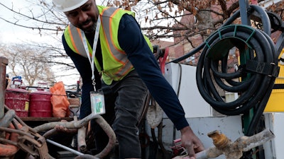 Blackhawk Sewer & Water contractor Khaild Waarith holds a lead pipe that was extracted in Chicago, April 10, 2023.