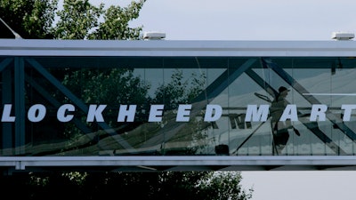 A man walks past a Lockheed Martin logo as he walks through a section of the company's chalet bridging a road at Farnborough International Airshow in Farnborough, southern England, July 19, 2006.