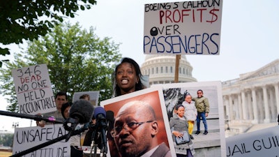 Zipporah Kuria of England, lost her father Joseph Kuria, one of the crash victims of a Boeing 737 MAX8 in Ethiopia, holds his photographs as she speaks during a news conference on Capitol Hill.