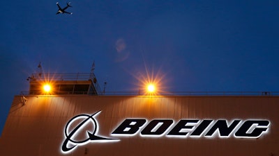 An airplane flies over a sign on Boeing's newly expanded 737 delivery center, Oct. 19, 2015, at Boeing Field in Seattle.