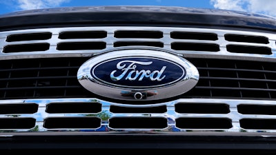 The Ford logo is shown on the grill of a pick-up truck on a dealership lot.