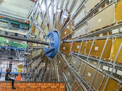 One side of the ATLAS detector. The technician on the left faces one of the wheels of the muon chambers – sensors to detect and measure muons.