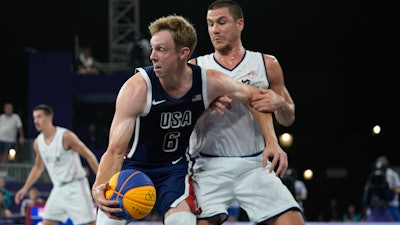 Canyon Barry of the United States fends off Mihailo Vasic of Serbia in the men's 3x3 basketball pool round match between Serbia and the United States at the 2024 Summer Olympics, Tuesday, July 30, 2024, in Paris, France.
