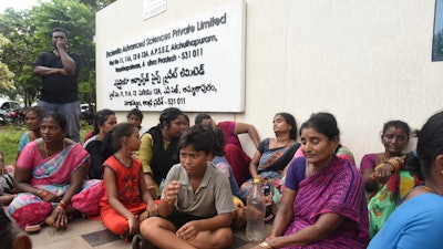 Relatives of the victims killed in a fire triggered by an explosion at the Escientia Advanced Sciences Private Ltd., a pharmaceutical company, sit outside the factory, in Atchutapuram, Andhra Pradesh state, India.
