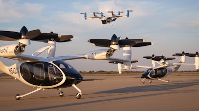 Two of Joby’s battery-electric production prototype aircraft in Marina, California, with the company’s hydrogen-electric technology demonstrator in flight above.