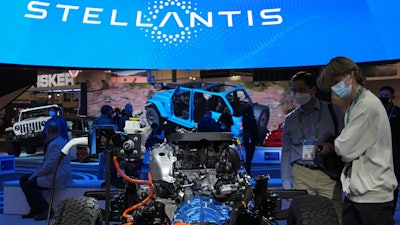 People look at the charging technology from the Jeep Wrangler 4xe at the Stellantis booth during the CES tech show Thursday, Jan. 6, 2022, in Las Vegas.