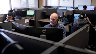 Stanley Solis, center, and other representatives take calls at an Alorica center in San Antonio, Aug. 19, 2024.