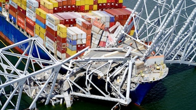 In this aerial image released by the Maryland National Guard, the cargo ship Dali is stuck under part of the structure of the Francis Scott Key Bridge after the ship hit the bridge, March 26, 2024, in Baltimore.