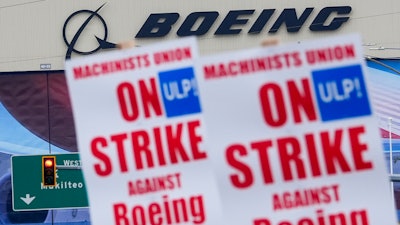 Boeing workers wave picket signs as they strike after union members voted to reject a contract offer, Sunday, Sept. 15, 2024, near the company's factory in Everett, Wash.