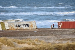 People walk past stranded containers in the area between Tranum and Slette beach in Denmark, Saturday, Dec. 23, 2023, a day after a Maersk ship dropped 46 containers off the coast between Bulbjerg and Svinkloev in the northwestern part of Jutland, during storm Pia.