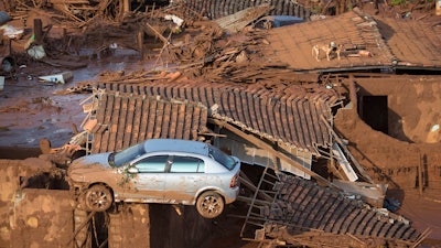 A car and two dogs are on the roof of destroyed houses at the small town of Bento Rodrigues after a dam burst in Minas Gerais state, Brazil, Nov. 6, 2015.