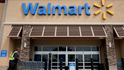 In this May 9, 2013, file photo, a worker pushes shopping carts in front of a Wal-Mart store in La Habra, Calif.