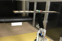 A large black cylinder with a plate attached at the front creates irregular turbulence under the tunnel's high-speed winds. The airfoil wing system with eight pressure sensors and a pitot tube is mounted on a load cell to measure the lift experienced by the system.