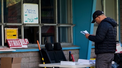 A Boeing employee looks at informational pamphlets before heading in to vote on a new contract offer from the company, Wednesday, Oct. 23, 2024, at the Aerospace Machinists Union hall in Renton, Wash.