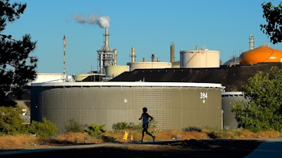 A jogger runs in front of the Phillips 66 refinery, July 16, 2014, in the Wilmington area of Los Angeles.