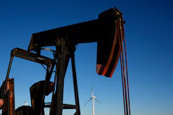 A pumpjack operates in the foreground as wind turbines at the Buckeye Wind Energy wind farm rise in the distance, Monday, Sept. 30, 2024, near Hays, Kan.