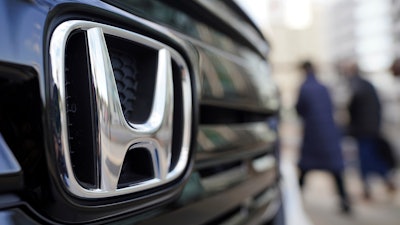 People walk near the logo of Honda Motor Company at a showroom on Feb. 8, 2022, in Tokyo.
