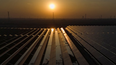 The sun sets over electric pylons along a solar farm near Weifang in eastern China's Shandong province on March 22, 2024.
