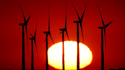 Wind turbines at the Buckeye Wind Energy are diffused by heat vapors as the are silhouetted against the rising sun, Sept. 30, 2024, near Hays, Kan.
