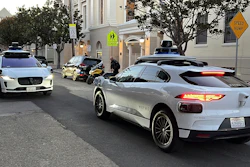 Two Waymo driverless taxis stop before passing one another on a San Francisco street on Feb. 15, 2023.