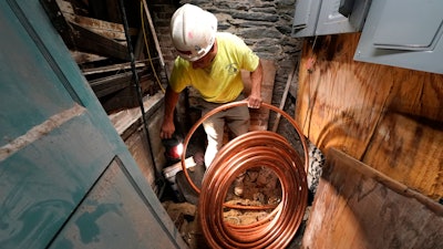George Philbin, of Boyle & Fogarty Construction, works to feed a new copper residential water supply line, after removing a old lead residential water supply line, in the basement of a home where service was getting upgraded, June 29, 2023, in Providence, R.I.
