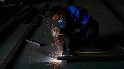 A worker welds together metal parts at the factory of Kam Pin Industrial (HK) Ltd, manufacturer of coated aluminum panels in Dongguan city in southern China's Guangdong province on Thursday, April 17, 2025.