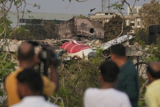 Onlookers watch wreckage from Thursday's Air India plane crash lying atop a building in Ahmedabad, India, Saturday, June 14, 2025.