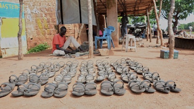 Shoemaker Emmanuel Achuil works under the shade of a tarpaulin in Wau, South Sudan, June 13, 2025.