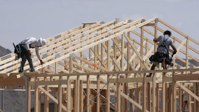 Construction workers frame up a roof of wood lumber at a new home build, April 1, 2025, in Laveen, Ariz.