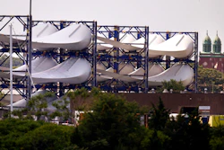 Giant wind turbine blades for the Vineyard Winds project are stacked on racks in the harbor, July 11, 2023, in New Bedford, Mass.