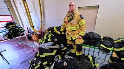 Firefighter Christopher Harrington stands next to the station's old turnout gear, while wearing recently issued non-PFAS turnout gear, at Fire Station 4 on July 3, 2025, in East Providence, R.I.