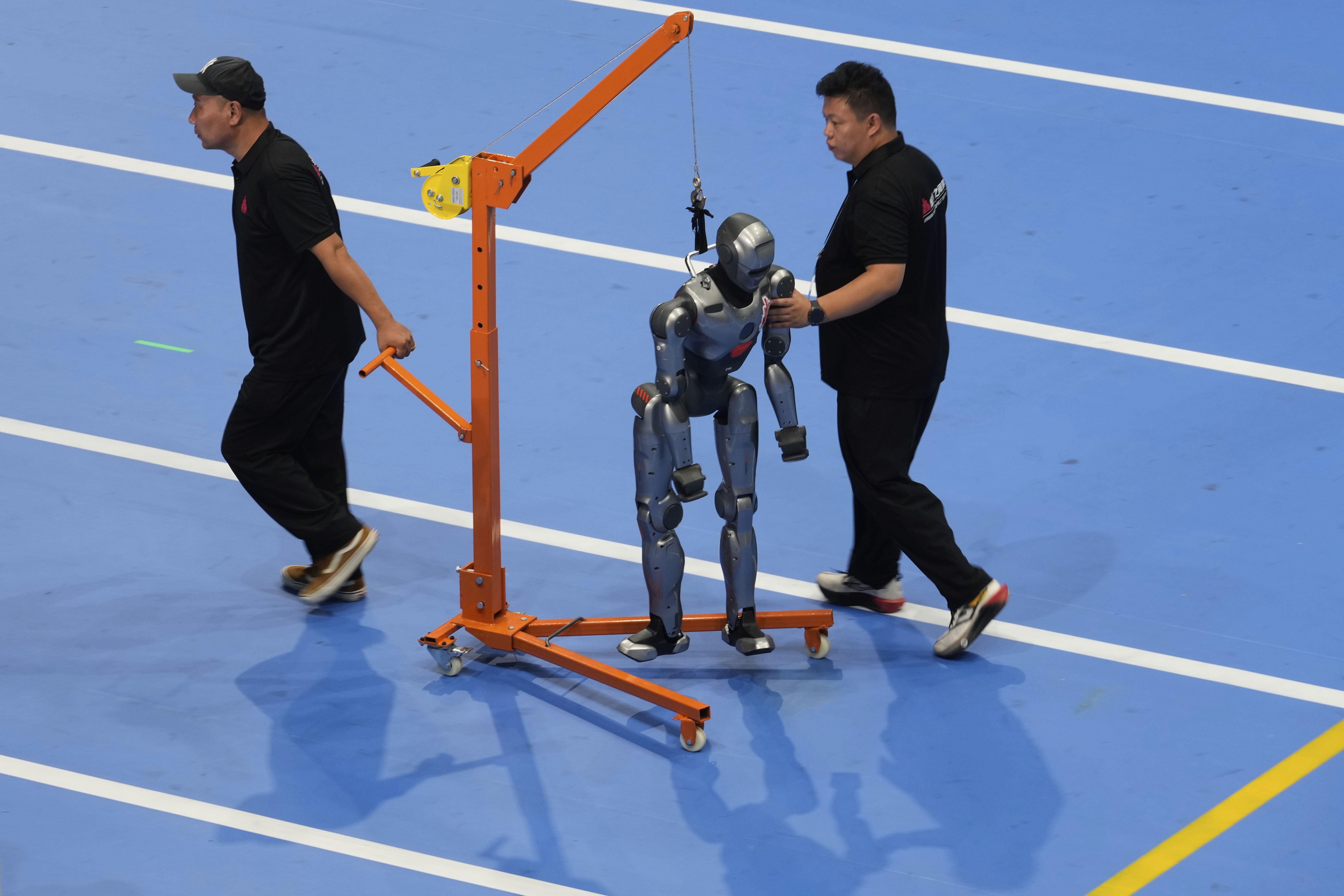 Workers transfer a robot before the opening ceremony for the World Humanoid Robot Games held in Beijing, China, Thursday, Aug. 14, 2025.