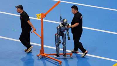 Workers transfer a robot before the opening ceremony for the World Humanoid Robot Games held in Beijing, China, Thursday, Aug. 14, 2025.