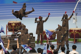 A human performer leaps above robots dressed like terracotta warriors during the opening ceremony of The World Humanoid Robot Games held in Beijing, China, Thursday, Aug. 14, 2025.