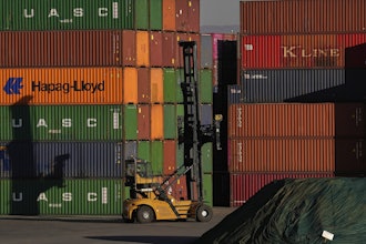 A heavy machine drives past shipping containers stacked at a depo, in Johannesburg, South Africa, Friday, Aug. 1, 2025.