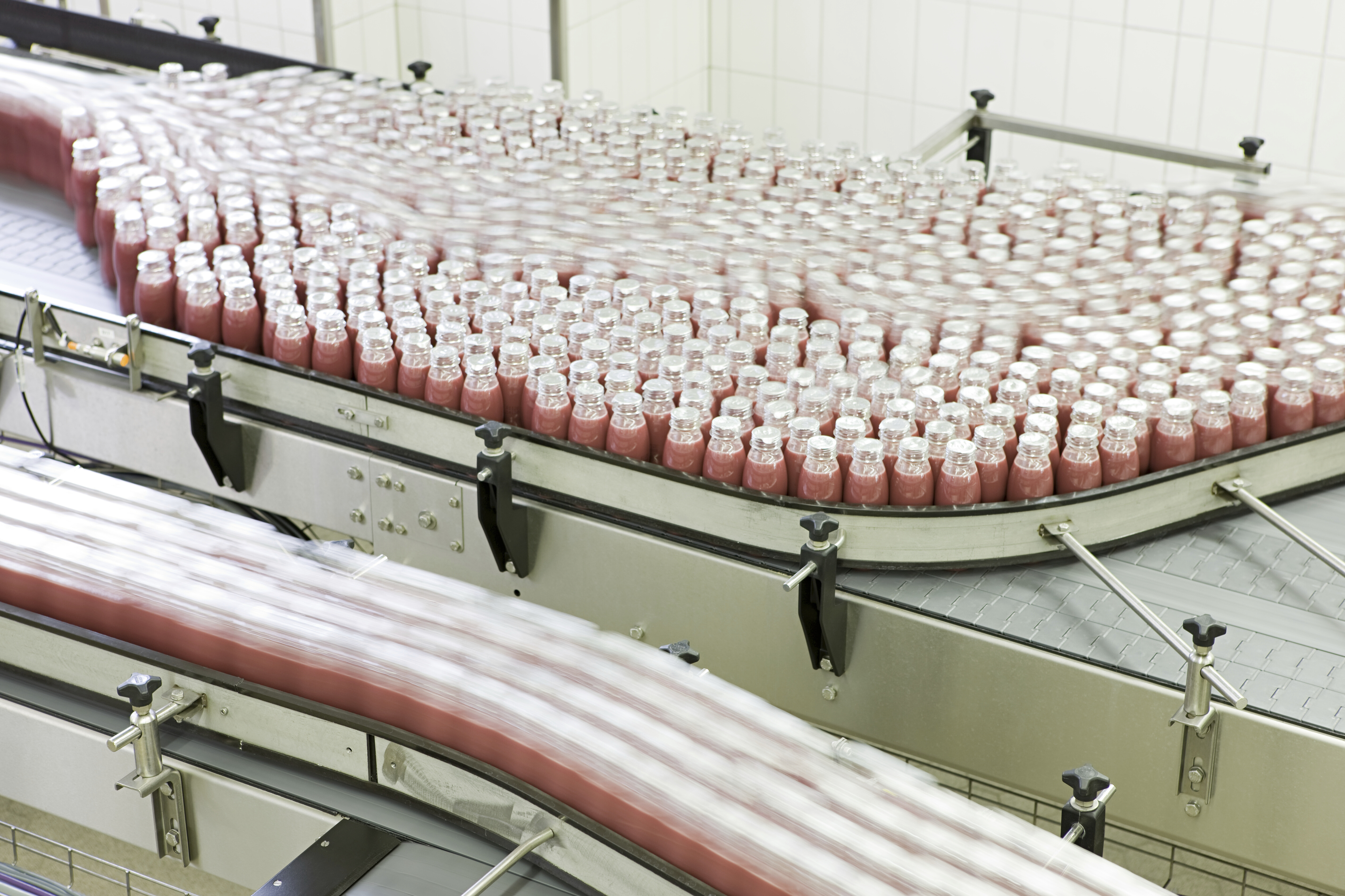 Bottling conveyor line with rows of glass bottles.