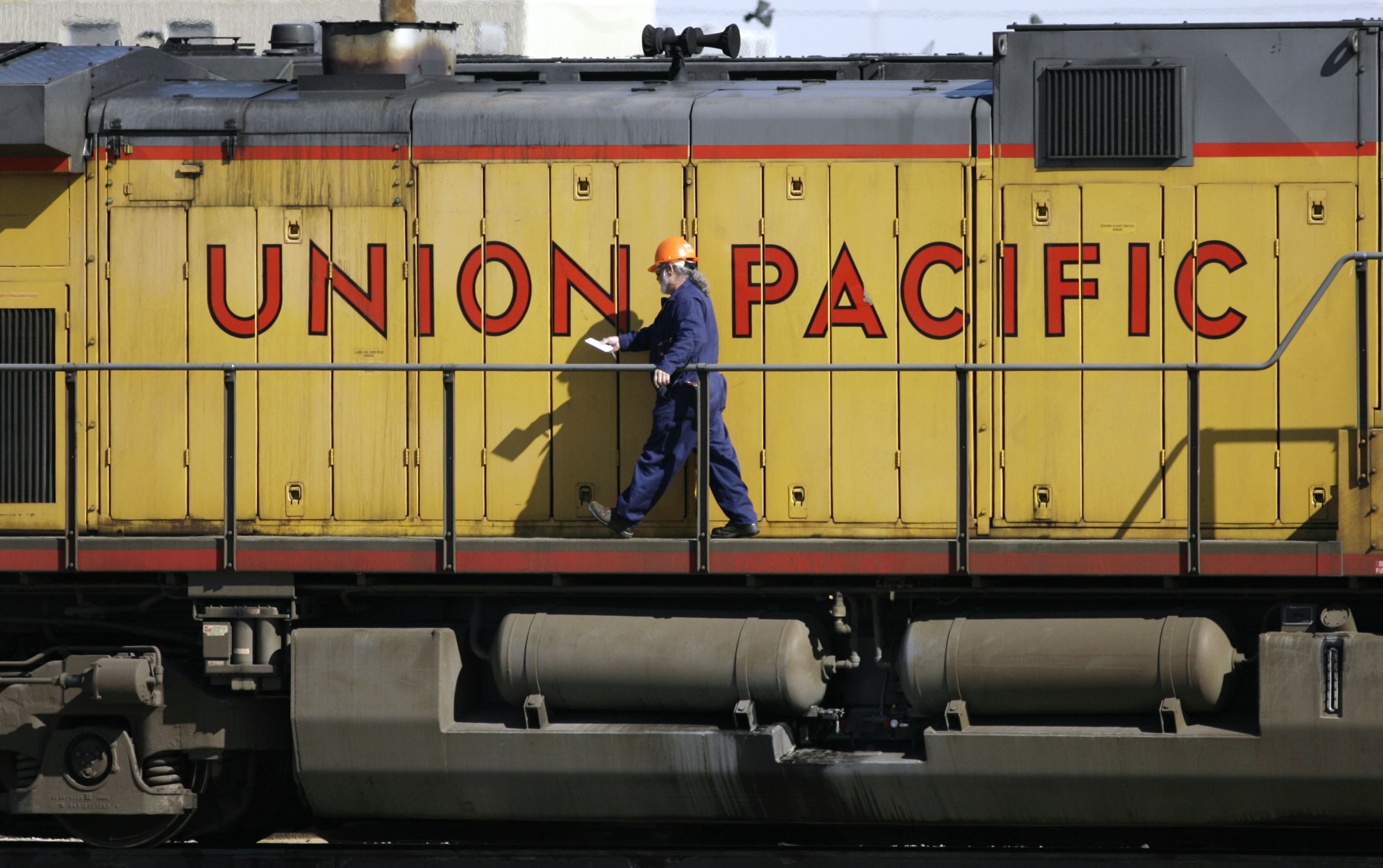A maintenance worker walks past a locomotive in the Union Pacific Railroad fueling yard in north Denver, Oct. 18, 2006.