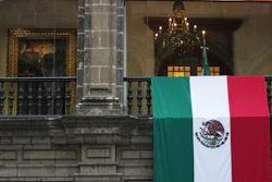 A Mexican flag hangs at the National Palace, where a portrait of former Mexico President Andres Manuel Lopez Obrador hangs, as President Claudia Sheinbaum delivers her first state-of-the-nation address in Mexico City, Monday, Sept. 1, 2025.