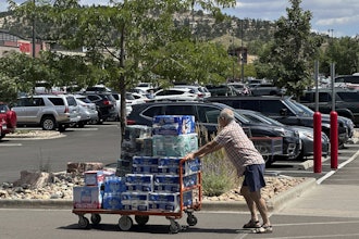 A shopper pushes a cart loaded with paper goods through the parking lot of a Costco warehouse, Aug. 12, 2025, Colorado Springs, Colo.