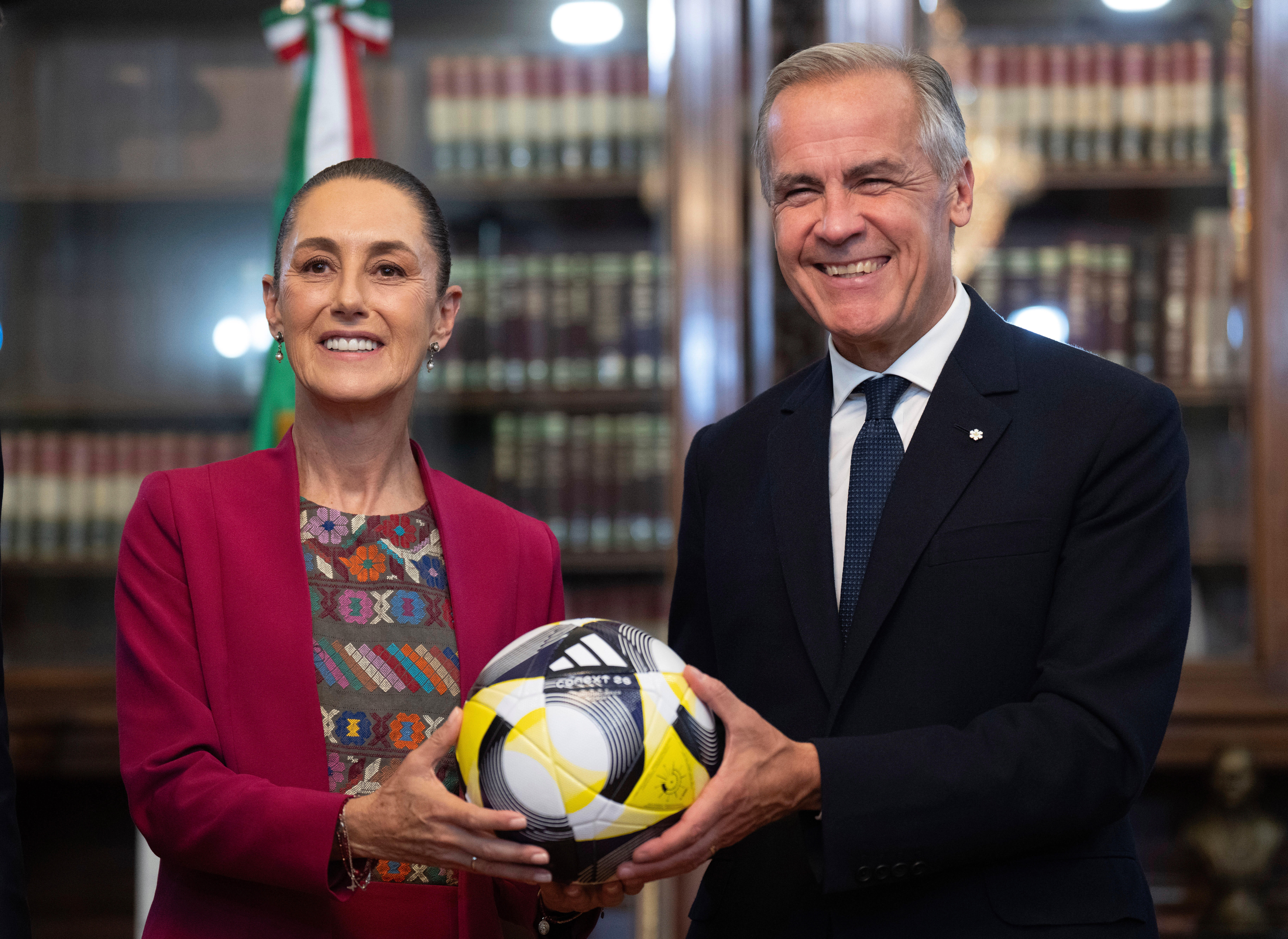 Canada's Prime Minister Mark Carney, right, presents Mexican President Claudia Sheinbaum with an official World Cup soccer ball before they meet at the Palacio National in Mexico City, Thursday, Sep 18, 2025.