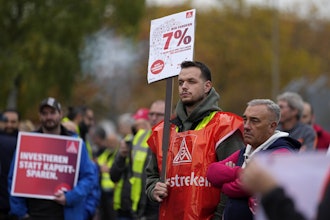 A worker holds a sign reading 'investing instead of saving' during a nationwide warning strike of the union IG Metal at the car maker FORD factory in Cologne, Germany, Germany, Oct. 29, 2024.